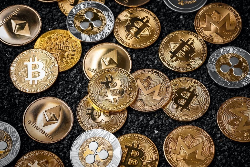 Bitcoinin, Ethereumin ja muiden kryptovaluuttojen symboleilla varustettuja kolikoita mustalla alustalla.