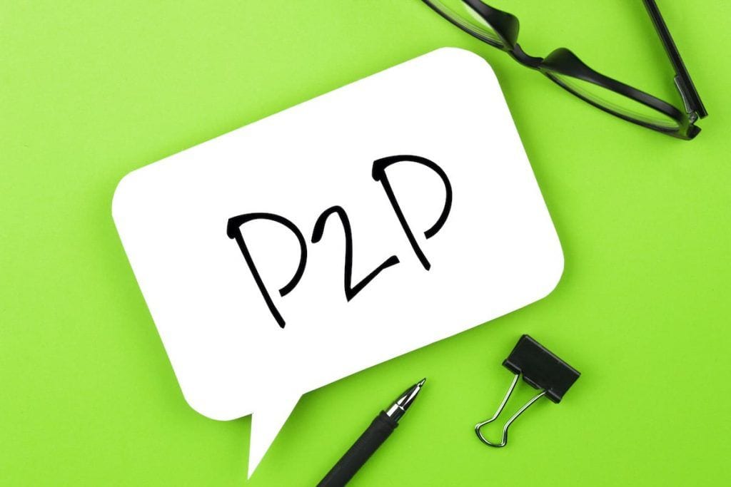 P2P-teksti valkoisessa puhekuplassa vihreällä alustalla, vieressä silmälasit, kynä ja paperipuristin.