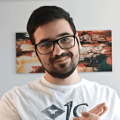 Florin Rața, cu barbă și ochelari negri, purtând un tricou alb, în fața unui tablou abstract.